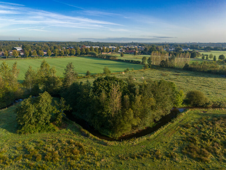 Luchtfoto met op de voorgrond de door het buitengebied van Bergeijk slingerende beek de Keersop. Op de achtergrond is de dorpskern Westerhoven te zien. - afbeelding vergroten